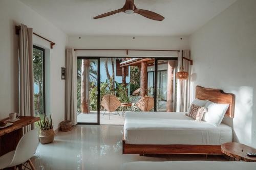 a bedroom with a bed with a ceiling fan and a patio at AmarBacalar in Bacalar