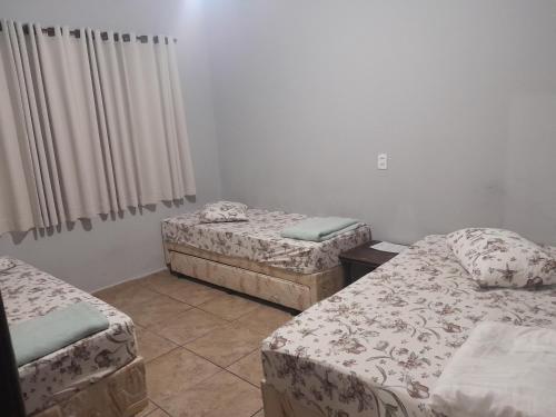 um quarto com três camas num quarto em Pousada Vitória em Aparecida