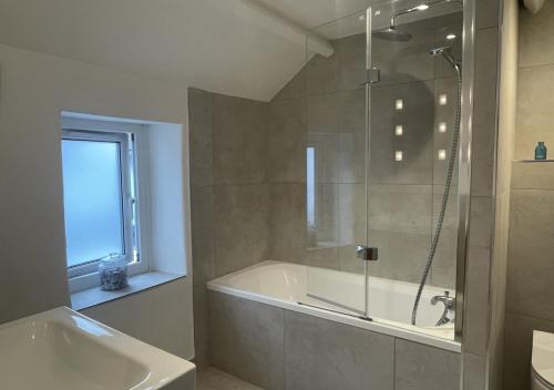 a bathroom with a shower and a tub and a sink at April Cottage in Brixham