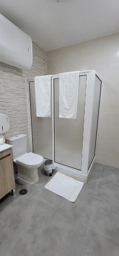 a bathroom with a toilet and a shower with towels at Alojamento Monte dos Patos in Setúbal