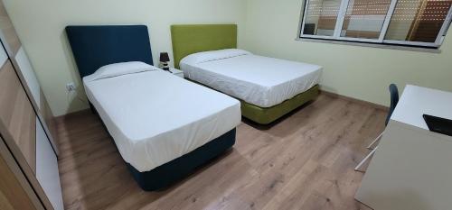 two beds in a small room with wooden floors at Alojamento Monte dos Patos in Setúbal