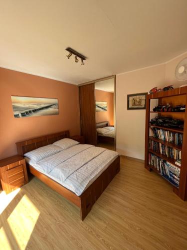 a bedroom with a bed and a book shelf at Apartament nad Zatoką Pucką in Swarzewo