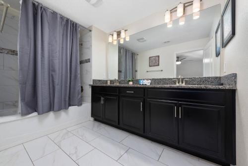 een badkamer met een zwarte wastafel en een spiegel bij House with pool in a resort in Kissimmee