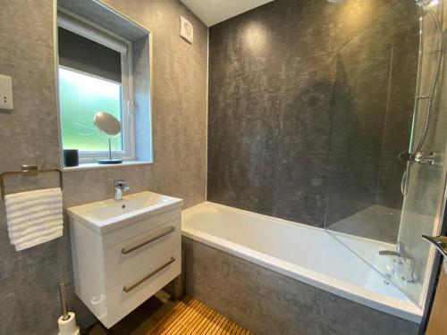 een badkamer met een bad, een wastafel en een douche bij A modern, dog-friendly 3 bedrm canal side property in Bolton le Sands