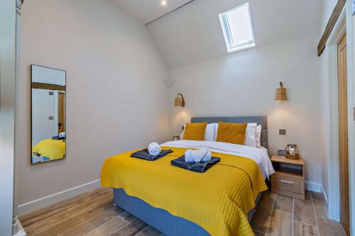 a bedroom with a bed with yellow sheets and a mirror at Dairy Barn by Bloom Stays in Groombridge