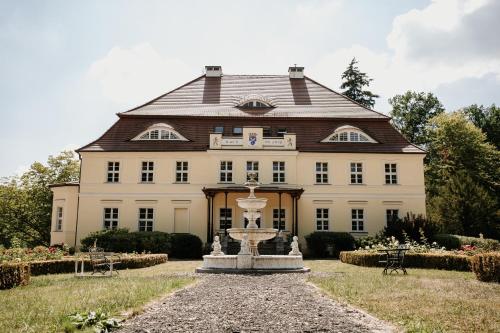 ein großes Gebäude mit einem Brunnen davor in der Unterkunft Pałac Bogaczów - hotel - restauracja in Bogaczów
