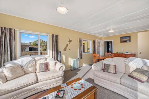 Una sala de estar con dos sofás blancos y una mesa. en Lakeside Escape - Motuoapa Holiday Home, en Turangi