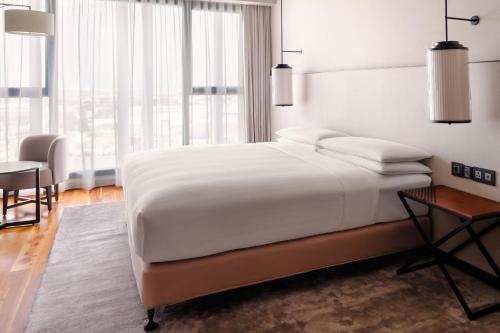 a white bedroom with a large bed and a table at Tunis Marriott Hotel in Tunis