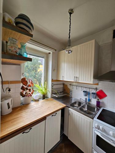 eine Küche mit weißen Schränken, einem Waschbecken und einem Fenster in der Unterkunft Lägenhet 