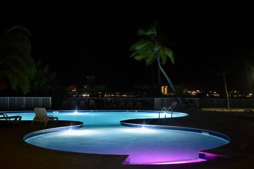 una piscina iluminada por la noche con luces moradas en Appartement Seacret, en Baie Nettle