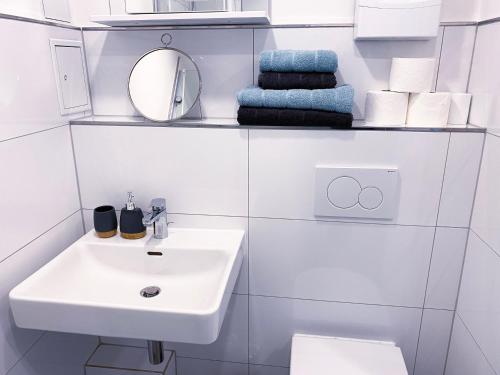 ein Badezimmer mit einem Waschbecken, einem Spiegel und Handtüchern in der Unterkunft NOVA Apartment- Phantasialand I Köln I Bonn in Brühl
