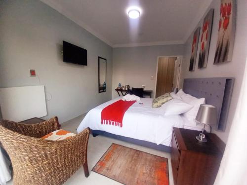 a bedroom with a white bed and two chairs at REALJOY GUEST SUITES in Centurion