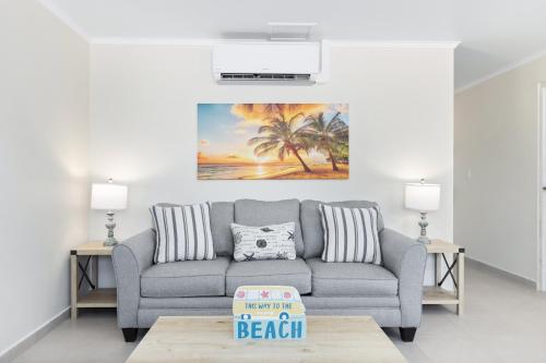 a living room with a gray couch and palm trees at Summerside 5 in Palm-Eagle Beach