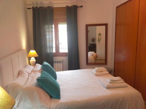 1 dormitorio con cama blanca con almohadas azules y espejo en CAN PLANAS Soleado, amplio con vistas y parking, en Sant Joan de les Abadesses