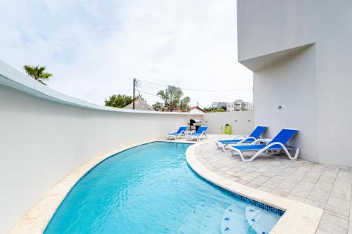a swimming pool with blue lounge chairs and a building at Summerside 5 in Palm-Eagle Beach
