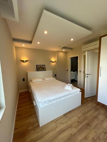 a bedroom with a large white bed and wooden floors at 3 min to beach, luxury building in Antalya