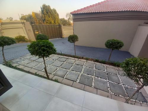 a garden with three trees and a building at REALJOY GUEST SUITES in Centurion
