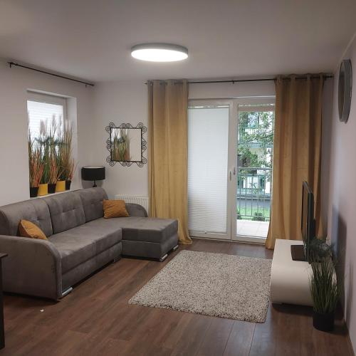 a living room with a couch and a tv at Apartament w Bursztynowych Komnatach in Darłówko