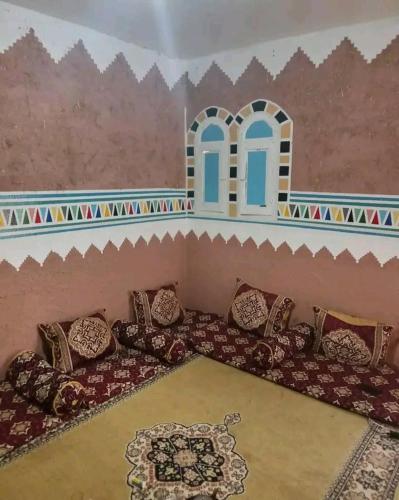 a room with a couch with pillows and a wall at Hostel Yahdih Dakhla in Dakhla