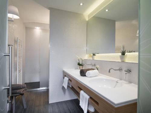baño con lavabo y espejo grande en Hotel Tirolensis, en Tesimo