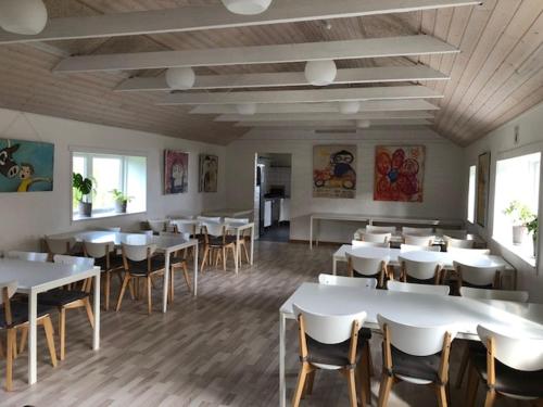 Morsø Friluftscenter في Erslev: غرفة طعام مع طاولات وكراسي بيضاء