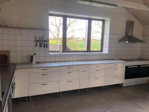 Morsø Friluftscenter في Erslev: مطبخ مع دواليب بيضاء ونافذة كبيرة