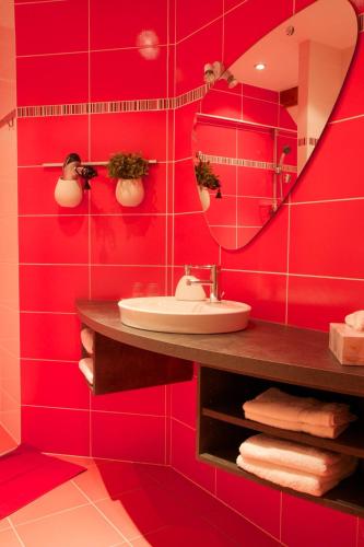 La salle de bains rouge est pourvue d'un lavabo et d'un miroir. dans l'établissement Le Grenier Des Arômes Au Domaine Wittmann, à Mittelbergheim