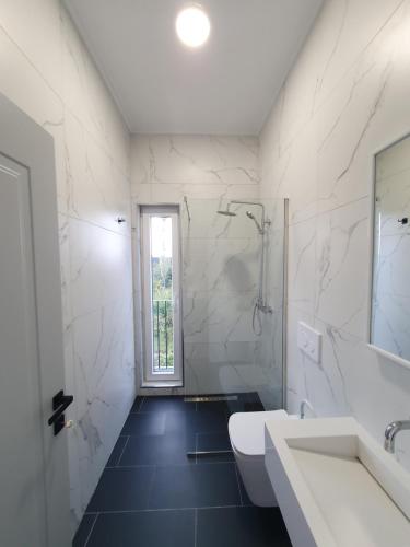 a white bathroom with a sink and a mirror at Nerium Garden Inn Tirana Airport in Rinas