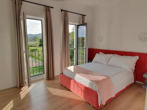 a bedroom with a bed and two large windows at Nerium Garden Inn Tirana Airport in Rinas