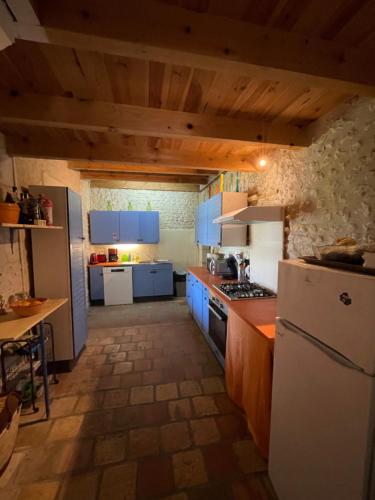 a kitchen with blue cabinets and a white refrigerator at charme de l'ancien au coeur de la vallée sud charentaise in Bardenac