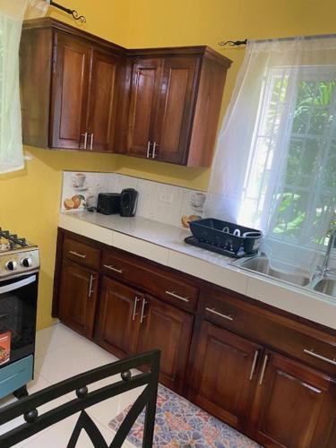 a kitchen with wooden cabinets and a sink and a window at Runthings Hideaway Stay Negril in Negril