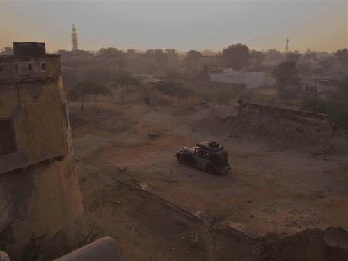 a vehicle sitting in a dirt field in a city at Narayan Niwas Castle in Rāmgarh