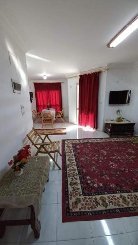 ein großes Wohnzimmer mit roten Vorhängen und einem TV in der Unterkunft شقق مفروشه in Madinat as-Sadis min Uktubar