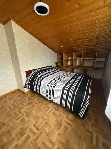 une chambre avec un lit noir et blanc et des plafonds en bois dans l'établissement Appartranquille, à Breuches