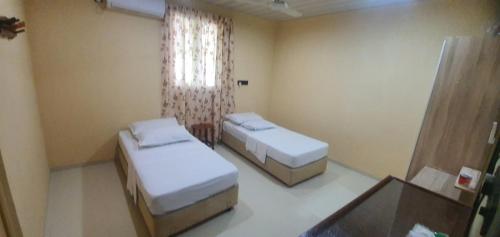 a bedroom with two beds and a window and a desk at Night Star Dhangethi in Dhangethi