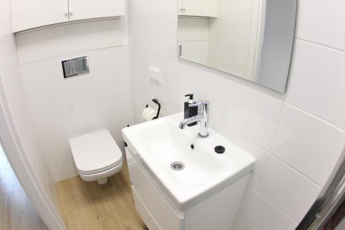 a white bathroom with a sink and a toilet at Komfi Dom 4 in Rzeszów