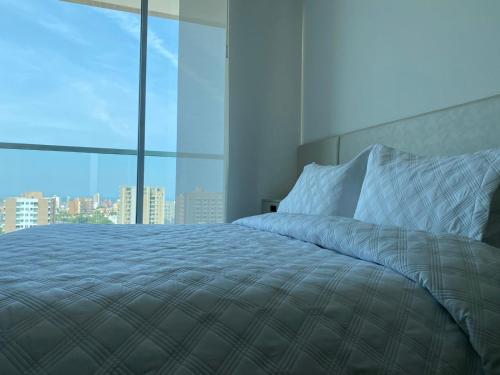 a bedroom with a large bed with a large window at Apartaestudio DISTRITO 90 in Barranquilla