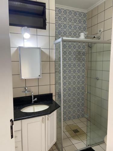 a bathroom with a sink and a glass shower at Apartamento lindo em Ubatuba - Centro in Ubatuba