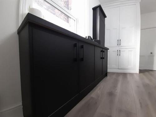 a large black cabinet in a white room at Chic 5 double bedroom house - 15 min to Manchester in Manchester