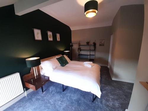 a bedroom with a large white bed and a lamp at Chic 5 double bedroom house - 15 min to Manchester in Manchester