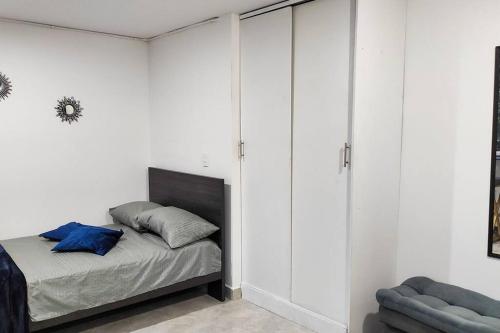um quarto com paredes brancas e uma cama com almofadas azuis em Práctico aparta estudio Envigado 301 em Envigado