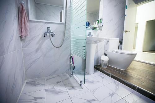 y baño blanco con ducha y aseo. en Hospitable House, en Seogwipo