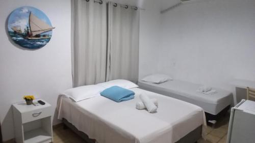 two beds in a room with white walls and a mirror at Pousada Águas Marinhas in Maceió