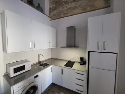 a white kitchen with a sink and a microwave at Apartamento El Arrumbador in Jerez de la Frontera