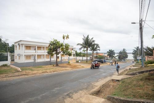 a street with a car driving down the road at Apartamento Vista Mar in São Tomé
