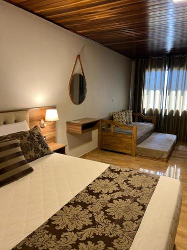 a bedroom with a large bed and a couch at Pousada Serra Geral in Cambará