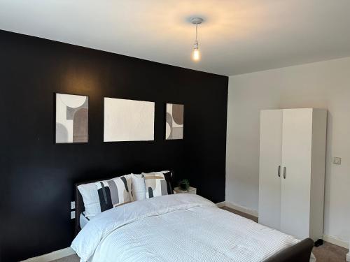 a bedroom with a black accent wall and a bed at Deluxe Spacious Room Near London Bridge! in London