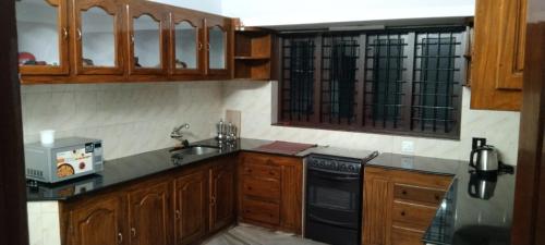 - une cuisine avec des placards en bois et un lave-vaisselle noir dans l'établissement Holiday homes in kidangoor kottayam kerala, à Kottayam