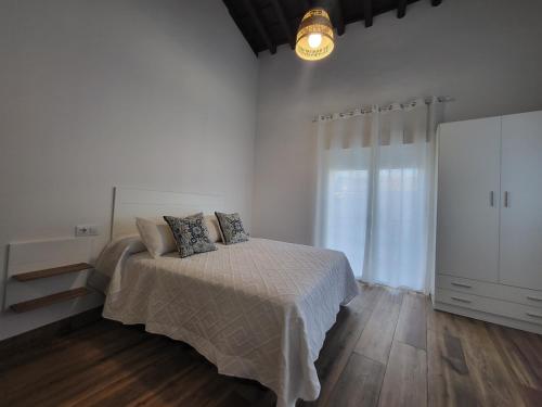 Dormitorio blanco con cama y ventana grande en Apartamento La Albariza, en Jerez de la Frontera