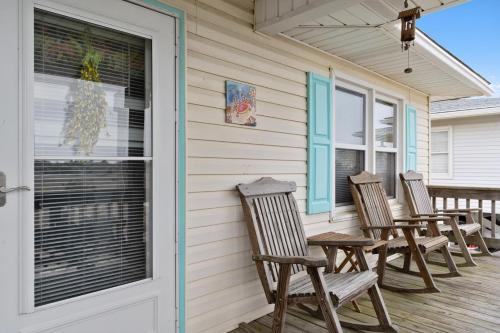 a row of chairs sitting on the porch of a house at Yellow Bird in Holden Beach